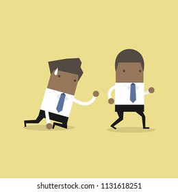 African businessman walks away from coworker crawling on the floor and calling out for help.