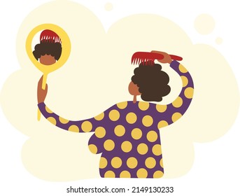 African woman combing her curly hair while looking in the mirror.