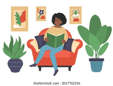 African woman reads book sitting on armchair at home. Relax, rest, leisure, education concepts