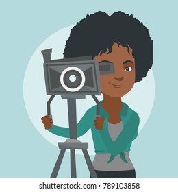 African-american cameraman looking through a movie camera on a tripod. Young cameraman with a professional video camera. Female cameraman taking a video. Vector cartoon illustration. Square layout.