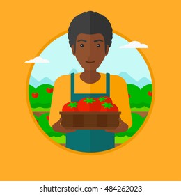 An african-american farmer holding a box with tomatoes. Happy farmer standing on the background of field with bushes of tomatoes. Vector flat design illustration in the circle isolated on background.