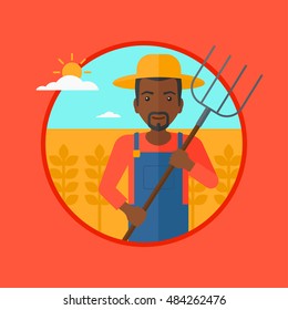 An african-american farmer standing with a pitchfork in wheat field. Man holding agricultural tool and working in wheat field. Vector flat design illustration in the circle isolated on background.