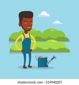 An african-american happy farmer standing near a watering can on the background of agricultural field with green bushes. Man watering plants in garden. Vector flat design illustration. Square layout.