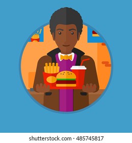 An african-american man holding tray full of junk food. Man in fast food restaurant. Man having lunch in a fast food restaurant. Vector flat design illustration in the circle isolated on background.