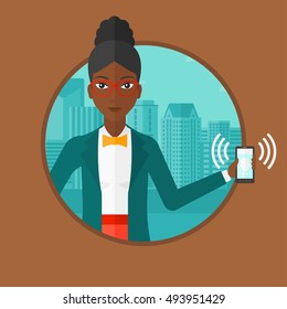 An african-american woman holding ringing mobile phone on a city background. Young smiling woman answering a phone call. Vector flat design illustration in the circle isolated on background.