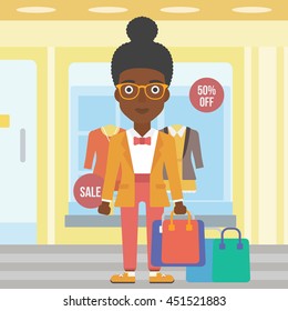 An african-american woman holding shopping bags on the background of boutique window with dressed mannequins. Happy young woman carrying shopping bags. Vector flat design illustration. Square layout.