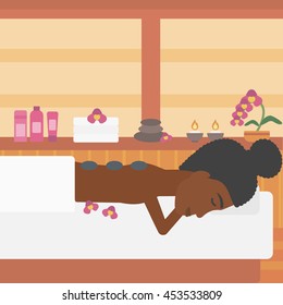 An african-american woman relaxing while getting stone therapy massage in the spa center. Woman having back massage in the spa salon. Vector flat design illustration. Square layout.