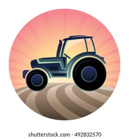 Agricultural tractor in a plowing field at sunrise