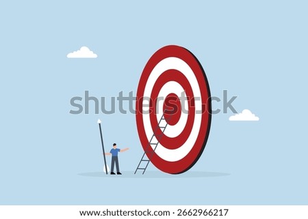 Aiming for high target mission, businessman with big ladder in his hand, starting to climb the ladder to bullseye.