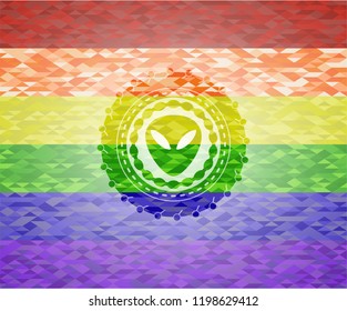 alien icon inside emblem on mosaic background with the colors of the LGBT flag