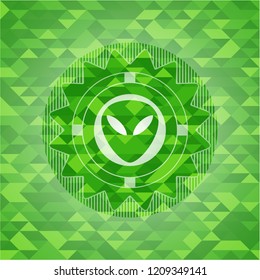 alien icon inside green emblem with triangle mosaic background