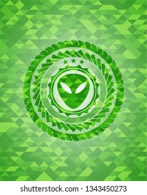 alien icon inside green emblem with triangle mosaic background
