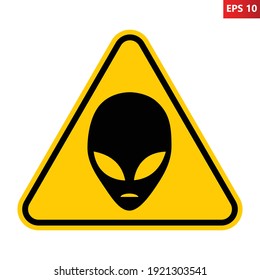 Aliens warning road sign. Vector illustration of yellow triangle warning sign with black alien head icon inside. Caution UFO activity area. Alien abduction symbol.