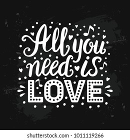 All you need is love hand drawn lettering on distressed chalk board. Handwritten white song words on black grunge background
