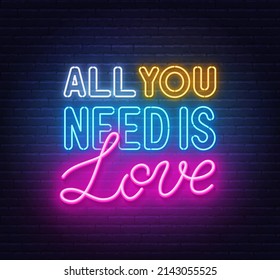 All you need is love neon lettering on brick wall background.