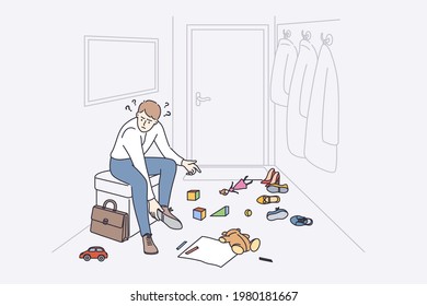 Anger and irritation concept. Young stressed man father cartoon character sitting at home feeling furious with child toys on floor putting off shoes vector illustration 