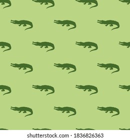 Animal seamless pattern and textile design. Vector illustration with green crocodile silhouette on light green background. Good for t-shirt design, fabric print, greeting card, wrapping, wallpapers.