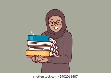 Arab little girl in hijab holds religious books with prayers in hands and looks at screen with smile. Arab child studying in religious school and reading textbooks to learn more about islamic religion