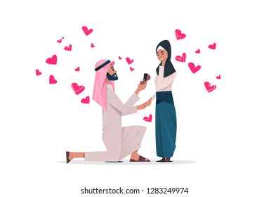 arab man kneeling holding engagement ring proposing arabic woman marry him happy valentines day concept couple in love marriage offer over heart shapes horizontal