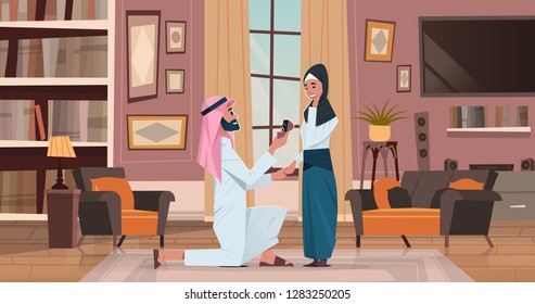 arab man kneeling holding engagement ring proposing arabic woman marry him couple in love wedding marriage offer happy valentines day concept living room interior