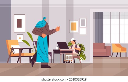 arab schoolboy using laptop little arabic boy with mother doing homework education concept living room interior