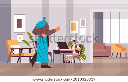 arab schoolboy using laptop little arabic boy with mother doing homework education concept living room interior