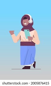 arab schoolgirl using smartphone and listening to music in headphones arabic girl with gadget vertical