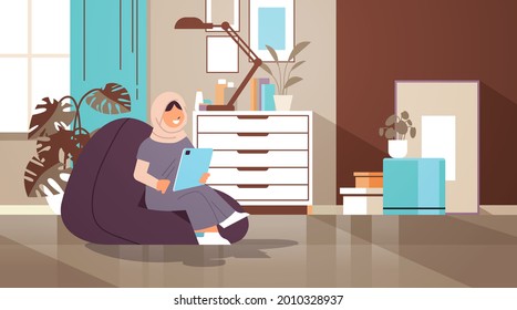 arab schoolgirl using tablet pc arabic girl sitting on beanbag and doing homework education concept