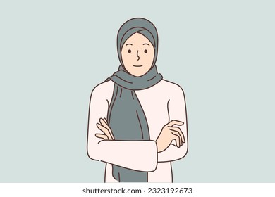 Arab woman in hijab stands with arms crossed and looks at screen for concept muslim style in clothing and diversity in fashion. Beautiful girl in hijab covering hair to comply with ethnic traditions