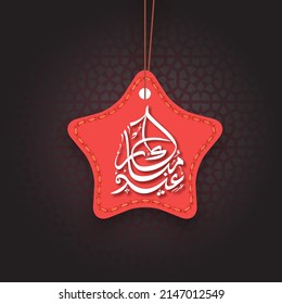 Arabic Calligraphy Of Eid Mubarak With Red Stitched Star Tag Hang On Black Background.