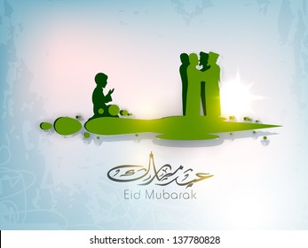 Arabic Islamic calligraphic text Eid Mubarak with silhouettes of Muslim peoples reading Namaj ( Islamic Prayer) and wishes each other. Concept for Muslim community holy festival Eid.