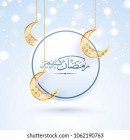 Arabic Islamic calligraphy of text Ramadan Kareem with hanging golden crescent moon on skyblue background. 