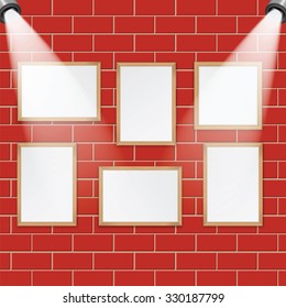 Art gallery and spotlights with place for your design.A set of wooden frames for paintings and photos on the brick wall are illuminated by lamps