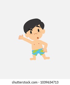 Asian boy in swimsuit something angry shows something to his right.
