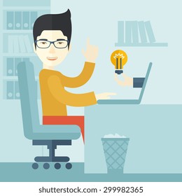 An asian businessman sitting while working infront of his desk getting a brilliant idea for business from the laptop. Business concept. A contemporary style with pastel palette soft blue tinted