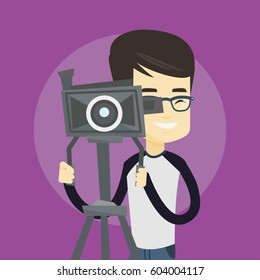 Asian cameraman looking through movie camera on a tripod. Young cameraman with professional video camera. Smiling cameraman taking a video. Vector flat design illustration. Square layout.