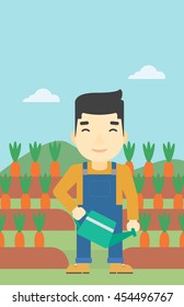 An asian farmer holding a watering can. Farmer watering carrots. Farmer standing on the background of carrots growing on field. Vertical layout.