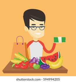 Asian male shopper standing at the table with grocery purchases. Young shopper holding money in hand in front of table with grocery purchases. Vector flat design illustration. Square layout.