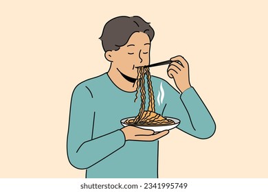 Asian man eats ramen with chinese sticks, enjoying taste of traditional national meal from korean cuisine restaurant. Guy stands and enjoys eating ramen or noodles to get enough during work break