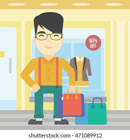 An asian man holding shopping bags on the background of boutique window with dressed mannequins. Happy young man carrying shopping bags. Vector flat design illustration. Square layout.