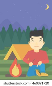 An asian man kindling a campfire on the background of camping site with tent. Tourist relaxing near campfire. Vector flat design illustration. Vertical layout.