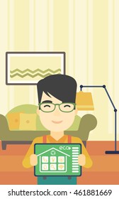 An asian man showing a tablet computer with smart home application on a screen on the background of living room. Vector flat design illustration. Vertical layout.