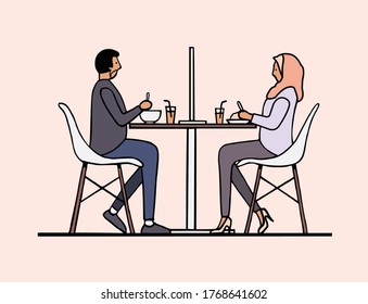 Asian Muslim woman and man dine and maintain social distancing with partition at restaurant to prevent and protect covid-19 coronavirus
