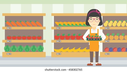 An asian young female supermarket worker holding a box with apples on the background of shelves with vegetables and fruits in supermarket. Vector flat design illustration. Horizontal layout.