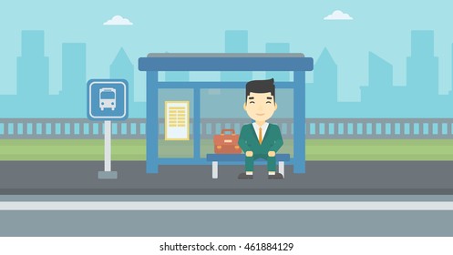 An Asian Young Man Waiting For A Bus At A Bus Stop On A City Background. Young Man Sitting At The Bus Stop. Vector Flat Design Illustration. Horizontal  Layout.