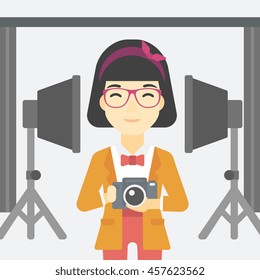 An asian young photographer holding a camera in photo studio. Photographer using camera in the studio. Woman taking photo with digital camera. Vector flat design illustration. Square layout.