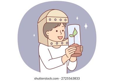 Un niño astronauta sostiene un árbol en un tubo de ensayo y sueña con cultivar plantas volando al espacio. Niño jugando astronauta y viajero cósmico, por concepto de búsqueda de vegetación fuera del planeta tierra