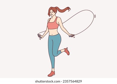 Mujer atlética saltando sobre una cuerda para mantenerse en forma, haciendo ejercicios físicos, vestida con ropa deportiva para el gimnasio. Jumping deportista disfruta de entrenamiento diario para mantenerse delgada y tener un cuerpo hermoso