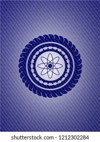atom icon inside emblem with jean background