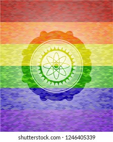 atom icon inside emblem on mosaic background with the colors of the LGBT flag